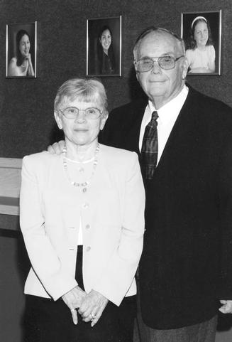 Bob & Joyce Wilson in front of photos of their grandchildren in Bob's office